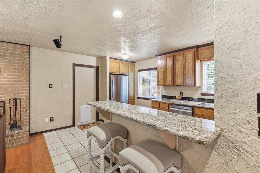 3702 Hastings Drive, Arlington, TX 76013 Functional galley kitchen with granite countertops, plentiful cabinet storage, stainless-steel dishwasher, tile flooring, and an adjacent dining area