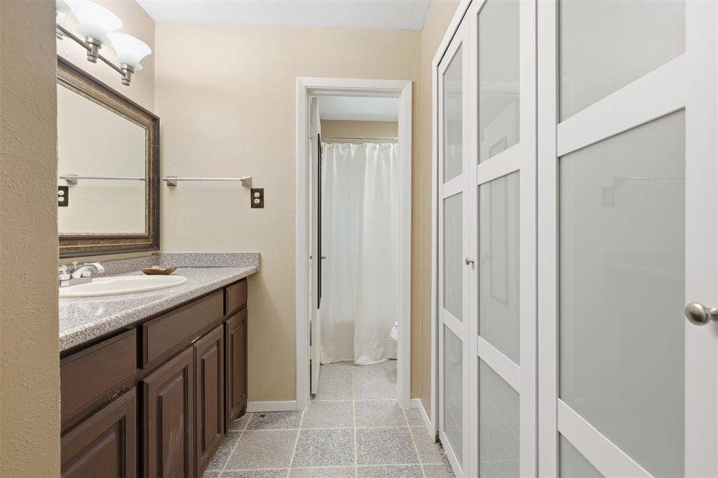 3702 Hastings Drive, Arlington, TX 76013 Dressing and vanity area with ample built-in storage, tile flooring, and access to the separate tub-and-shower room. New Closet Doors (7/2026)