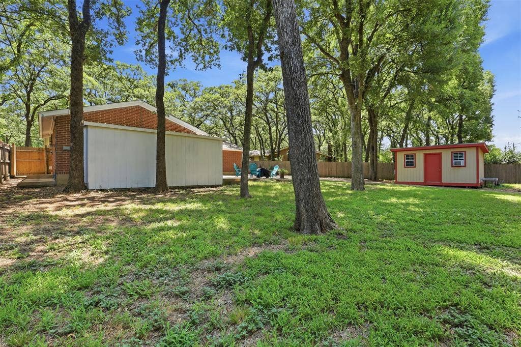 3702 Hastings Drive, Arlington, TX 76013 Spacious fenced backyard with a large patio, mature trees, attached two-car garage, and covered storage area in Arlington’s Woodland West neighborhood