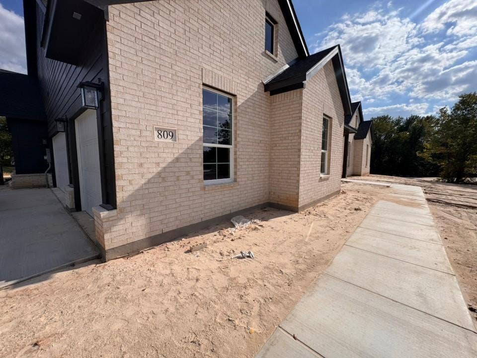 809 Zachary Michael Court, Springtown, TX 76082 Light-toned brick exterior with dark trim and a gabled roofline