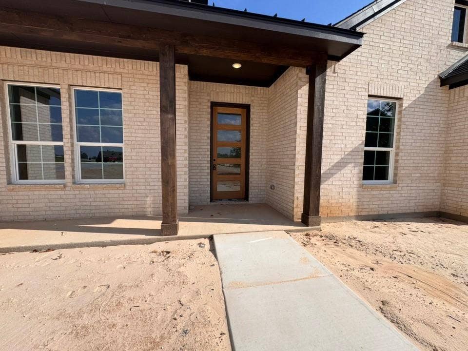 809 Zachary Michael Court, Springtown, TX 76082 Light-toned brick exterior with dark wood-finish columns and front door