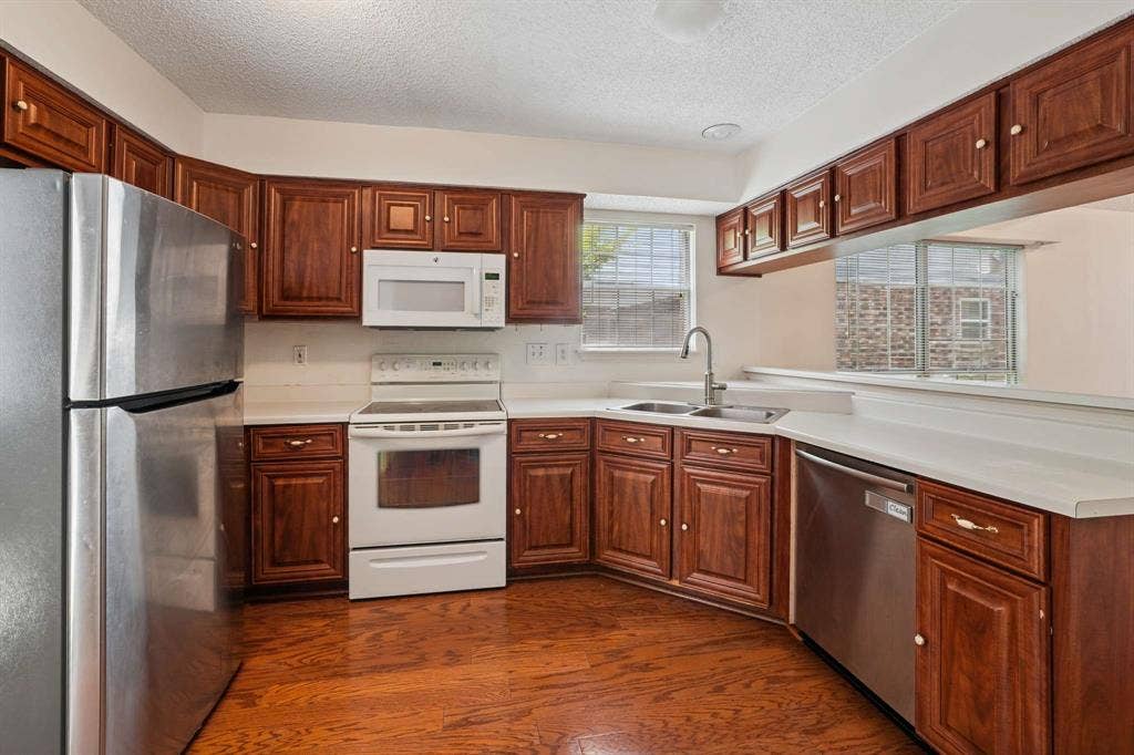 Kitchen featuring wood-finish flooring, dark wood cabinetry, white countertops, and a stainless steel refrigerator