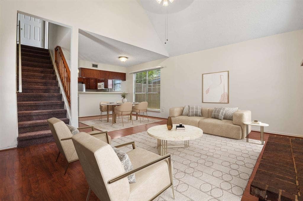 Spacious living area featuring vaulted ceilings, wood-finish flooring, and a brick fireplace