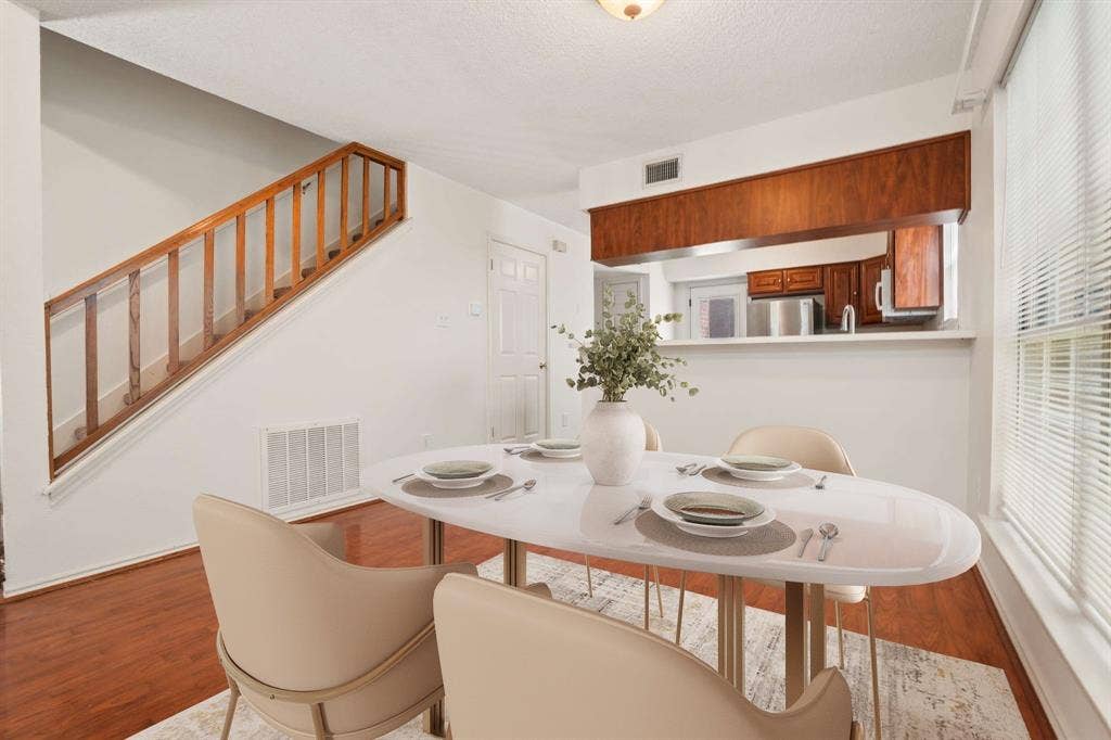 Dining area featuring wood-finish flooring and a pass-through window to the kitchen