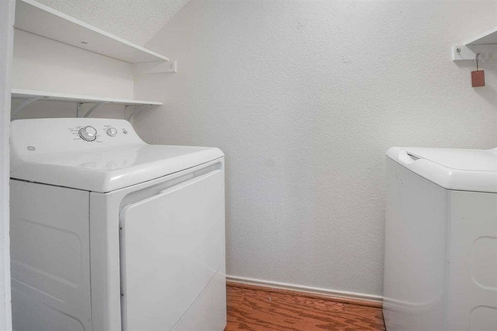 Dedicated laundry area featuring a white washing machine, white dryer, and wood-finish flooring