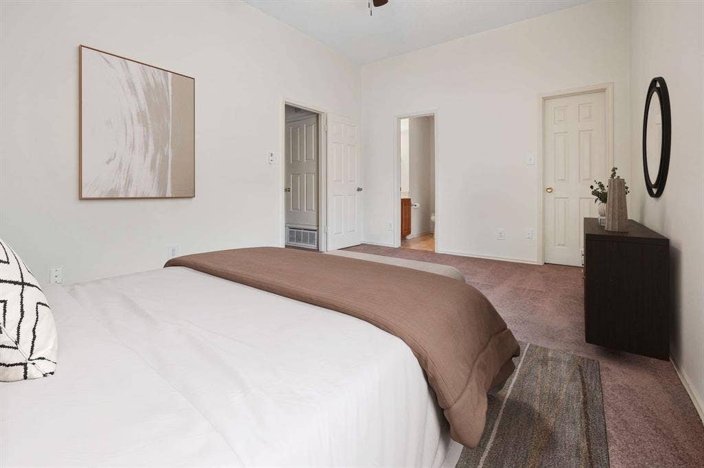 Spacious bedroom featuring neutral wall tones and a ceiling fan