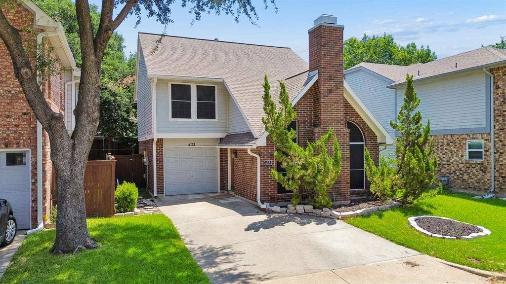 Brick and siding exterior featuring a prominent brick chimney, arched window, and attached garage