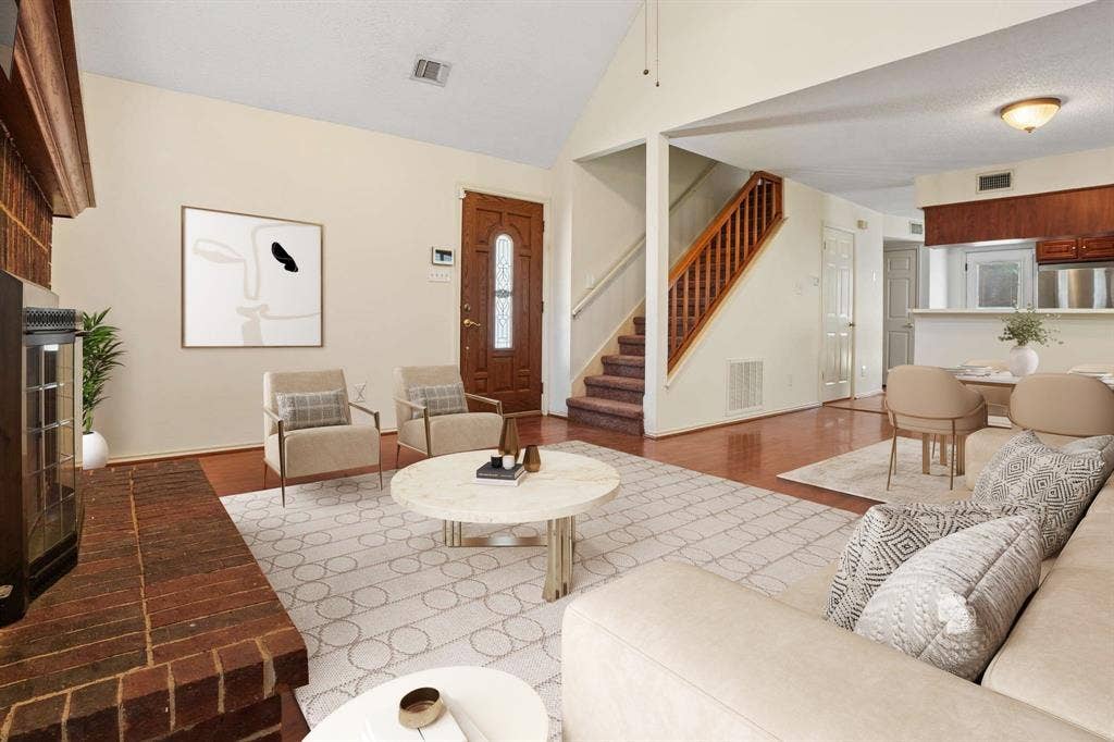 Living area featuring a brick fireplace, wood-finish flooring, and a vaulted ceiling