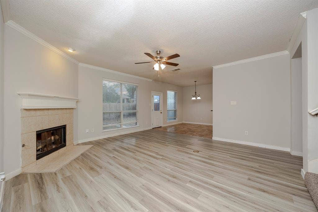 12475 Cajun Drive, Frisco, TX 75035 Living space featuring light wood-finish flooring, a tile-surround fireplace with a mantel, a ceiling fan, and a large window
