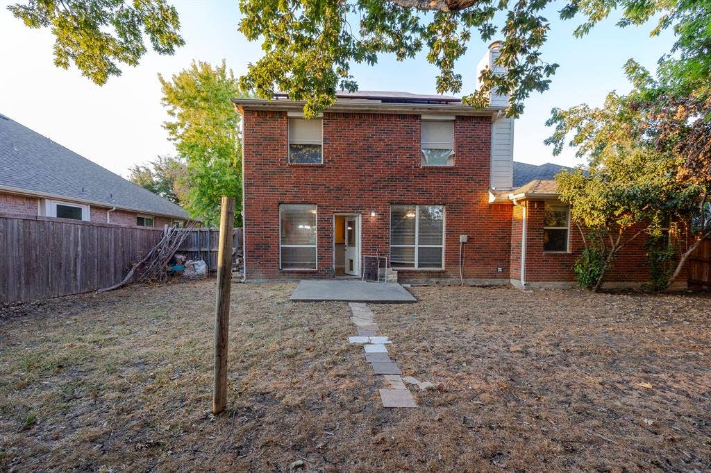 12475 Cajun Drive, Frisco, TX 75035 Brick exterior with multiple windows, a concrete patio, and a stone-paver walkway
