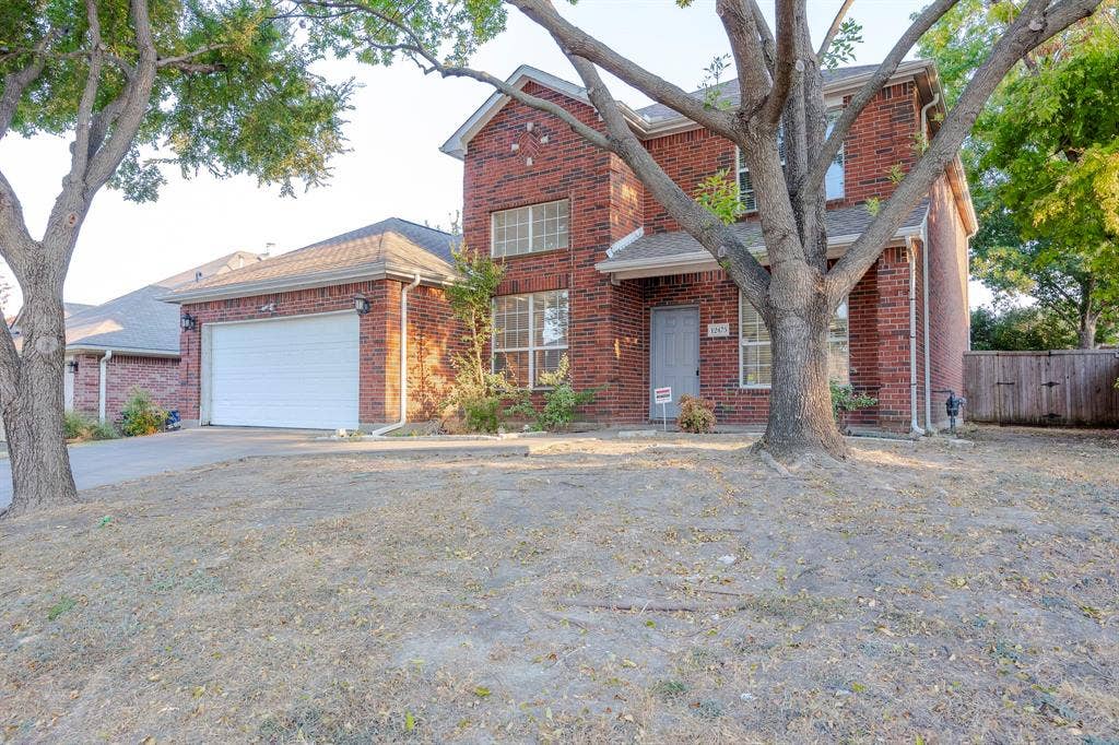 12475 Cajun Drive, Frisco, TX 75035 Two-story brick exterior with a two-car garage, front entry door, and a partially fenced yard