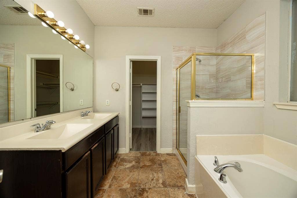 12475 Cajun Drive, Frisco, TX 75035 Dual vanity with integrated sinks, a built-in soaking tub, a stand-alone shower with a glass enclosure, and wood-finish flooring