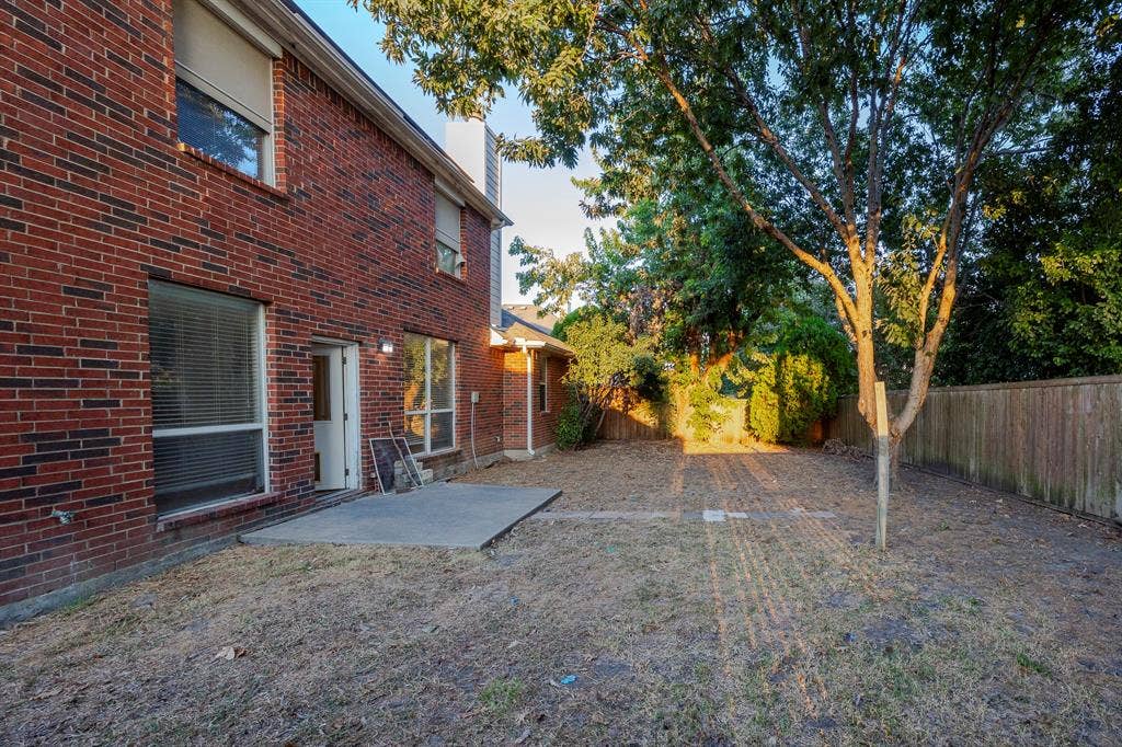 12475 Cajun Drive, Frisco, TX 75035 Brick exterior with multiple windows, a concrete patio, and mature trees in the yard