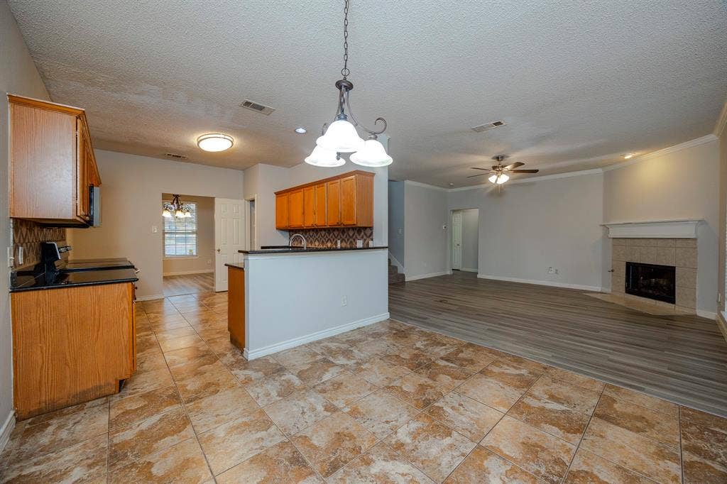 12475 Cajun Drive, Frisco, TX 75035 Kitchen with wood cabinetry, black countertops, and a tiled backsplash