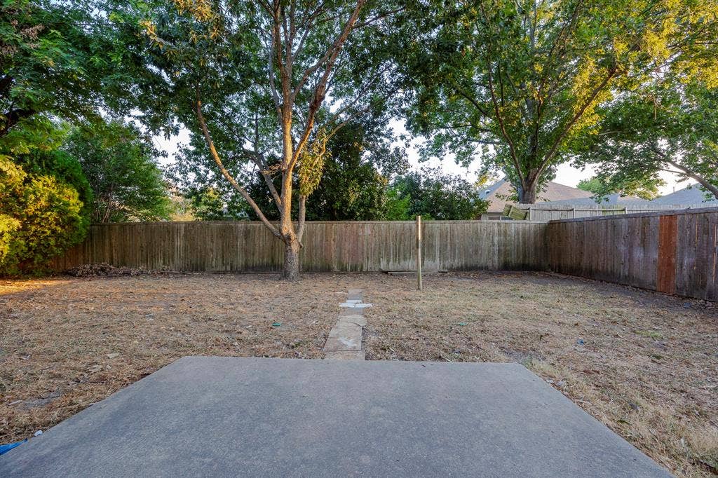 12475 Cajun Drive, Frisco, TX 75035 Spacious backyard featuring a concrete patio, wood fencing, mature trees, and a stone-paver walkway