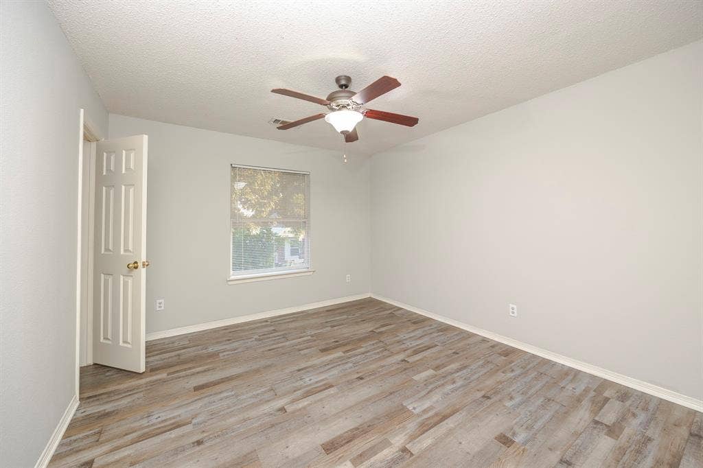 12475 Cajun Drive, Frisco, TX 75035 Neutral wall paint with wood-finish flooring, a ceiling fan with integrated lighting, and a window providing natural illumination