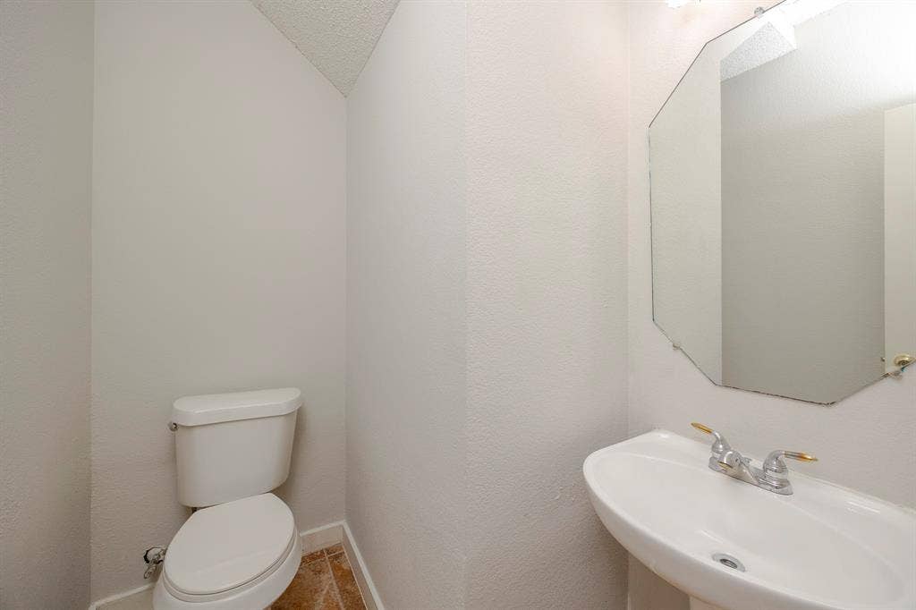 12475 Cajun Drive, Frisco, TX 75035 Pedestal sink, wall-mounted mirror, ceramic toilet, and tile flooring