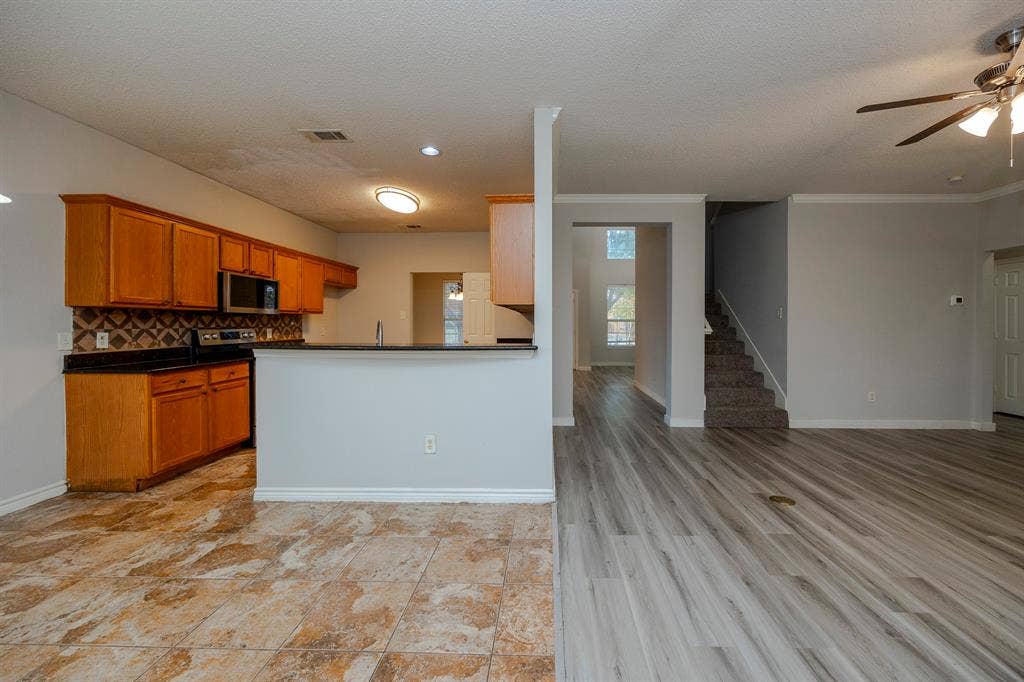 12475 Cajun Drive, Frisco, TX 75035 Kitchen with wood cabinetry, stainless steel appliances, and dark countertops