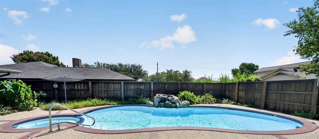 3310 Raintree Drive, Plano, TX 75074 Resort-style backyard featuring a sparkling pool, spa, waterfall, and plenty of space for outdoor entertaining
