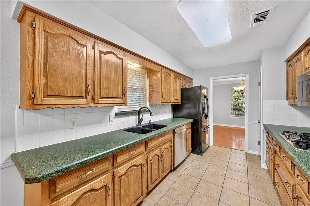 3310 Raintree Drive, Plano, TX 75074 Galley kitchen including double oven, gas stove top, microwave oven, and refrigerator (conveys with home)