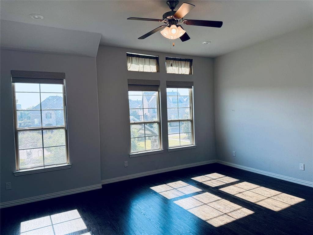 2455 Cathedral Drive, Richardson, TX 75080 Spacious room featuring multiple windows, wood-finish flooring, a ceiling fan with integrated lighting with motorized blinds