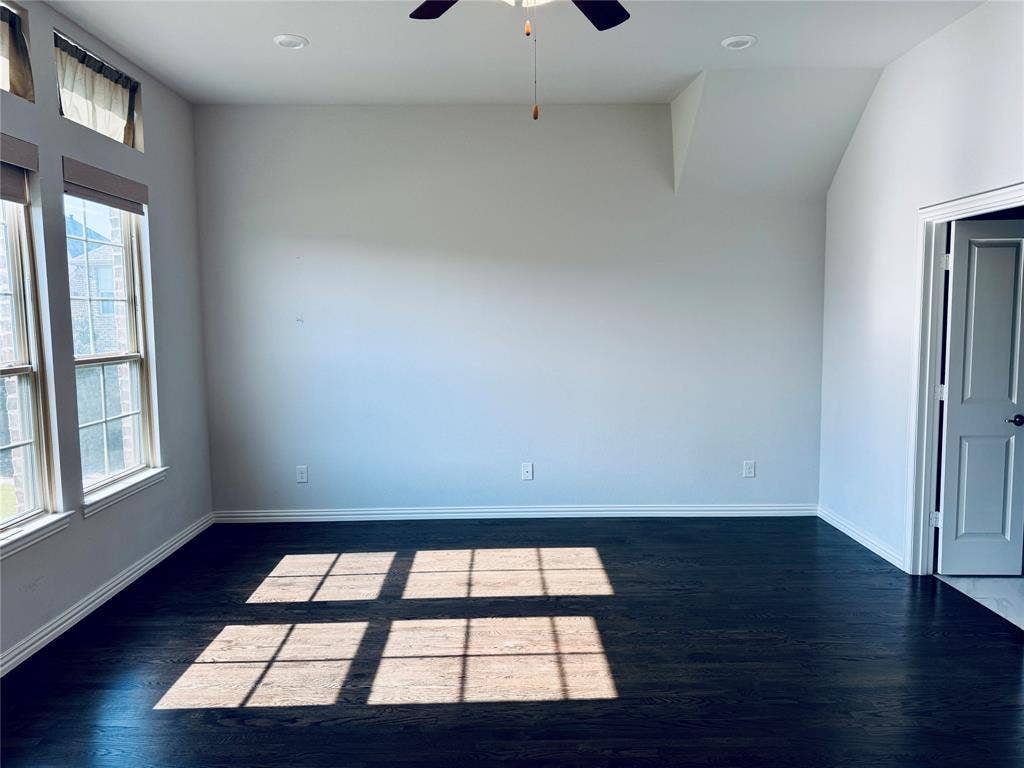 2455 Cathedral Drive, Richardson, TX 75080 Spacious room featuring dark wood-finish flooring, white walls, and a vaulted ceiling