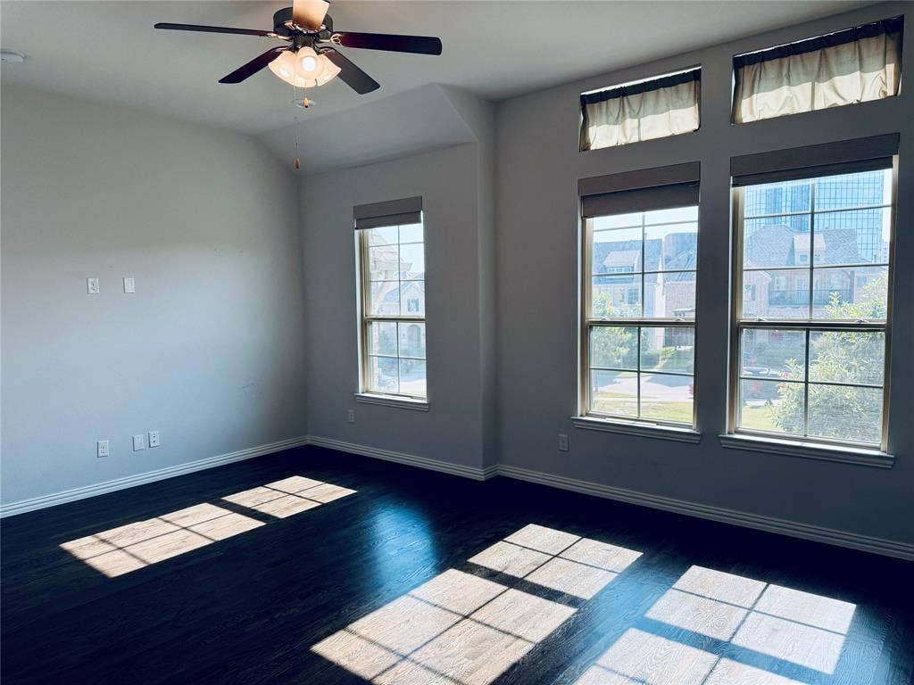 2455 Cathedral Drive, Richardson, TX 75080 Spacious room featuring dark wood-finish flooring, light neutral-toned walls, and a motorized blinds