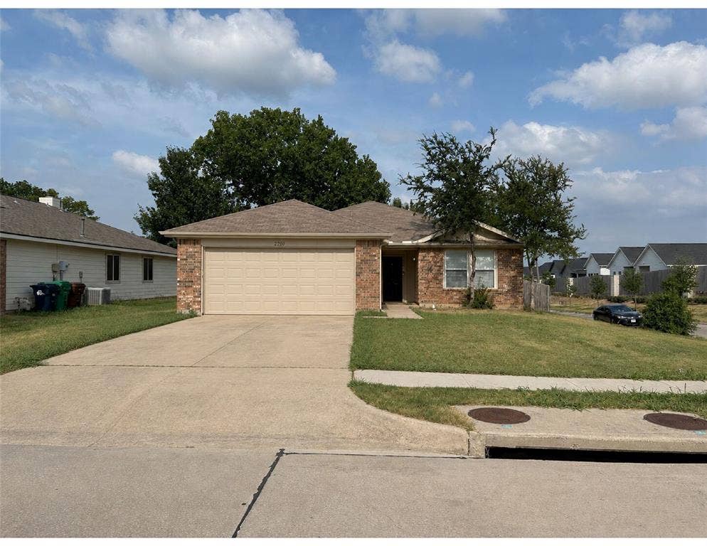 2200 Lookout Lane, Denton, TX 76207 Brick exterior featuring a two-car garage, concrete driveway, and a front yard with mature landscaping