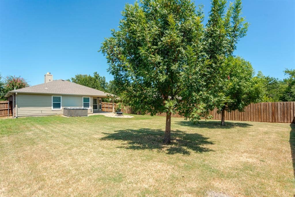 805 Andrews Court, Anna, TX 75409 Expansive backyard with a covered patio, privacy fencing, and mature trees