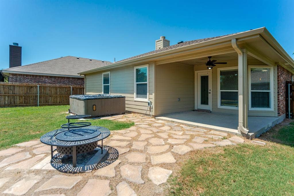 805 Andrews Court, Anna, TX 75409 Spacious primary bedroom showcasing warm wood-finish flooring, a ceiling fan with integrated lighting, dual windows with plantation shutters providing natural light, and a coordinating upholstered bench at the foot of the bed