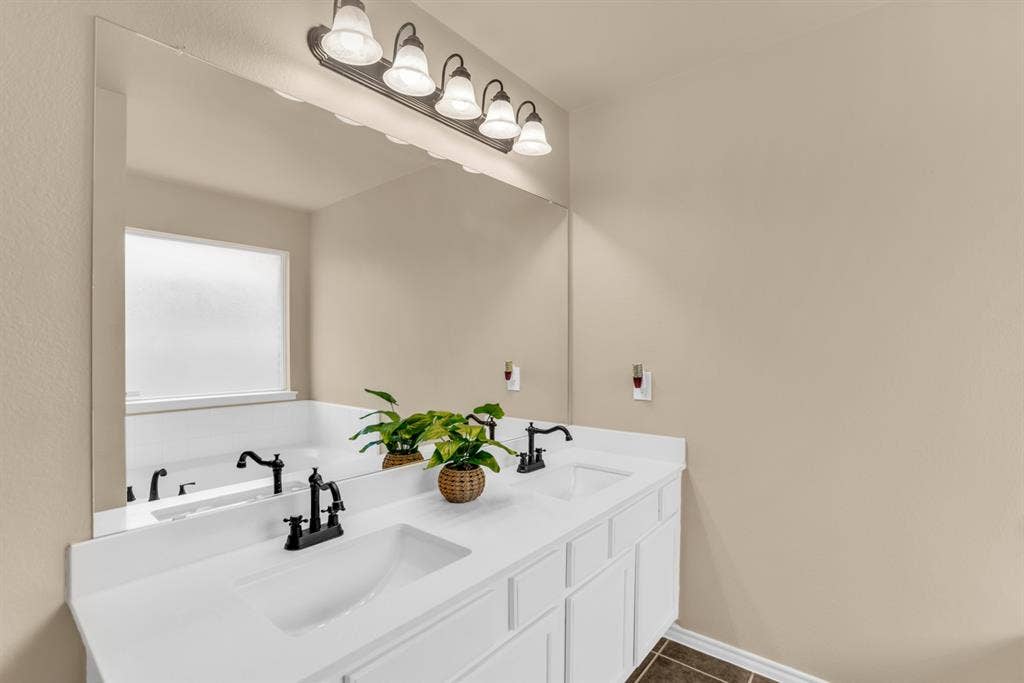 805 Andrews Court, Anna, TX 75409 Completely update bathroom with double vanity with white integrated sinks, matte black hardware, and an expansive mirror