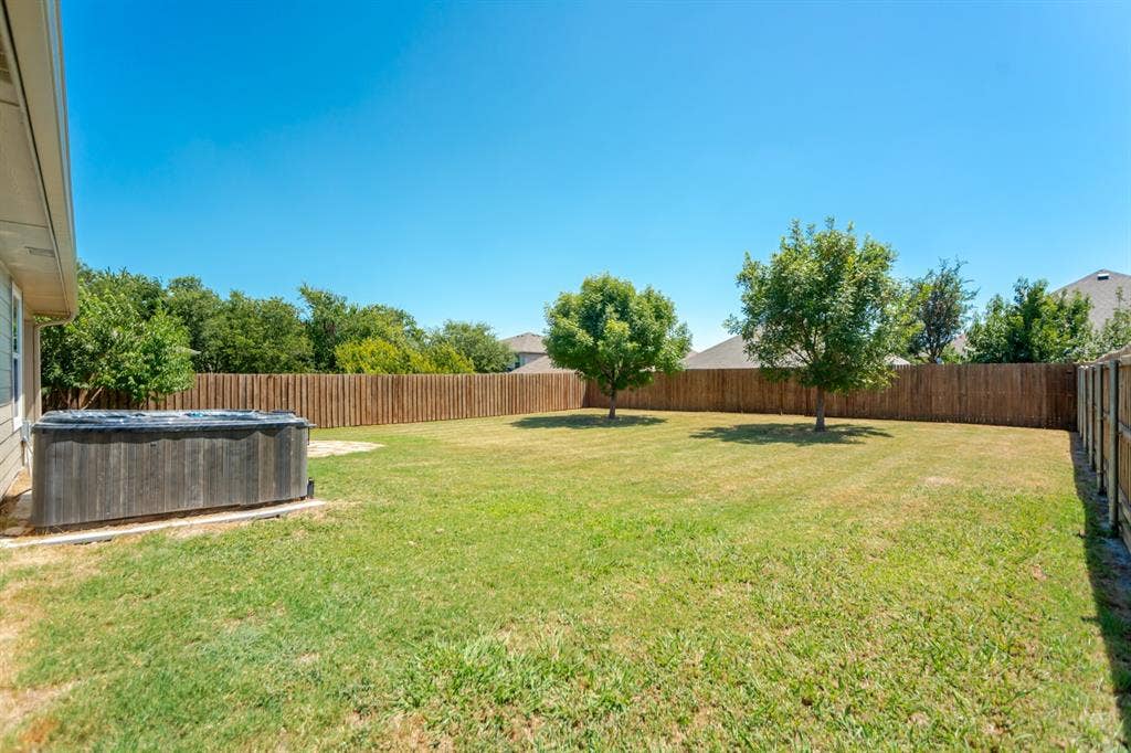805 Andrews Court, Anna, TX 75409 Expansive backyard featuring a wood-paneled spa, privacy fencing, two mature trees, and a substantial lawn area