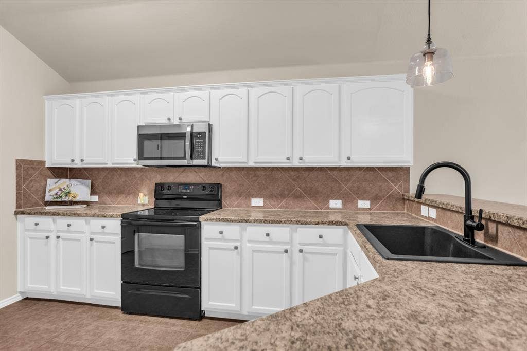 805 Andrews Court, Anna, TX 75409 White cabinetry with arched panel doors, tile backsplash, black range, and stainless steel microwave