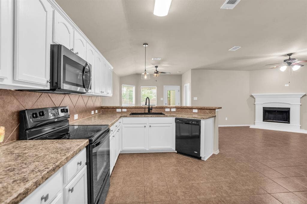 805 Andrews Court, Anna, TX 75409 Kitchen featuring white cabinetry, a built-in microwave, tiled backsplash, and a breakfast bar