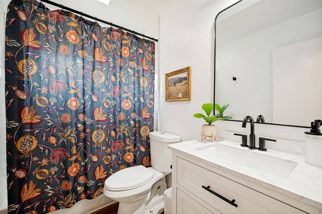 8420 Christie Drive, Frisco, TX 75033 Full Bath with Tub/Shower combination, White Vanity and decorative countertop and integrated sink, matte black faucet, and a large black-framed mirror