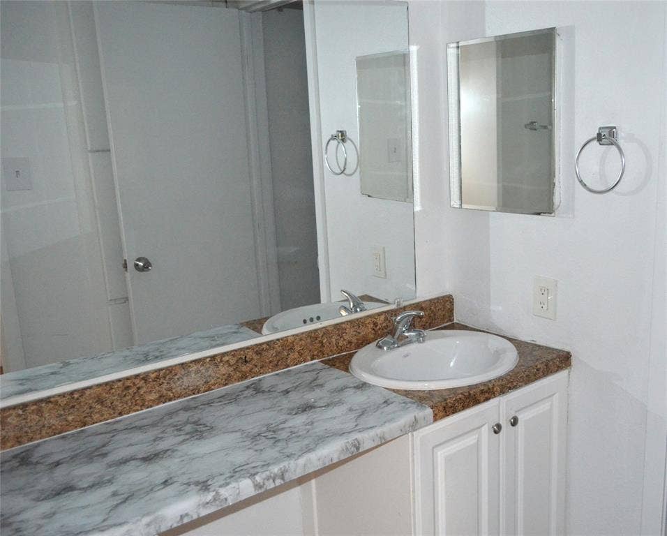 5500 Boca Raton Boulevard, #426, Fort Worth, TX 76112 Vanity area featuring a drop-in sink, white cabinetry with silver hardware, and a countertop with both a stone-look and speckled finish