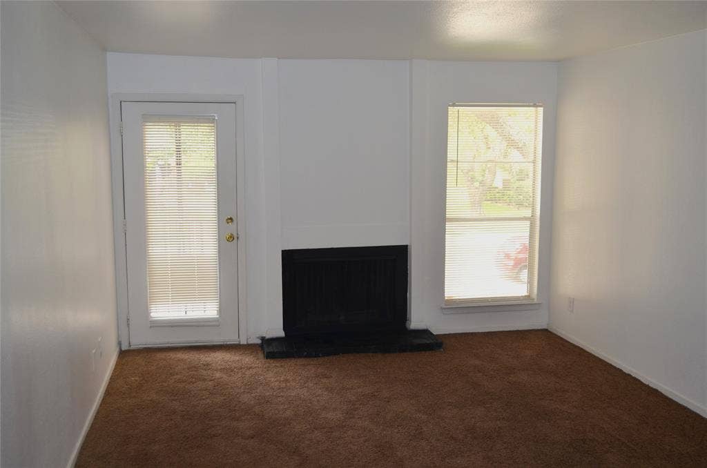 5500 Boca Raton Boulevard, #426, Fort Worth, TX 76112 Living area featuring a fireplace, a glass-paneled door with integrated blinds, and a large window with blinds