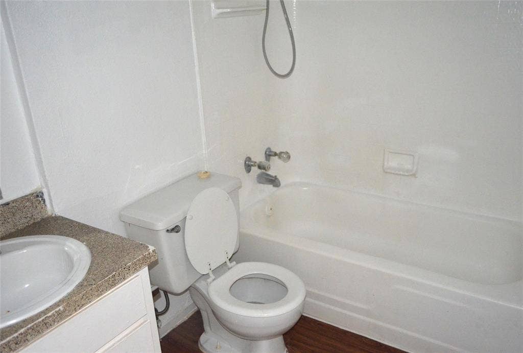 5500 Boca Raton Boulevard, #426, Fort Worth, TX 76112 Bathroom featuring a white bathtub, white toilet, and a vanity with a white basin and speckled countertop