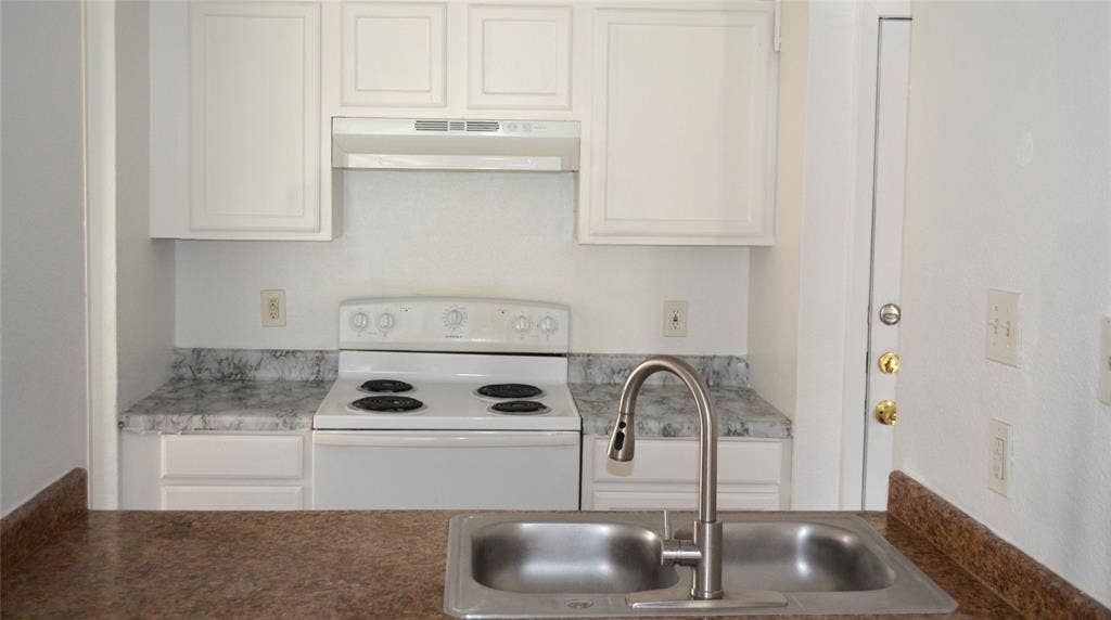 5500 Boca Raton Boulevard, #426, Fort Worth, TX 76112 Kitchen featuring a double basin stainless steel sink with a high-arch faucet, white electric range with overhead ventilation, white cabinetry, and variegated countertops
