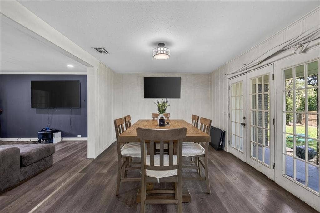 925 Maryland Drive, Athens, TX 75751 Dining area featuring wood-finish flooring, white vertical wall paneling, and a modern flush-mount light fixture