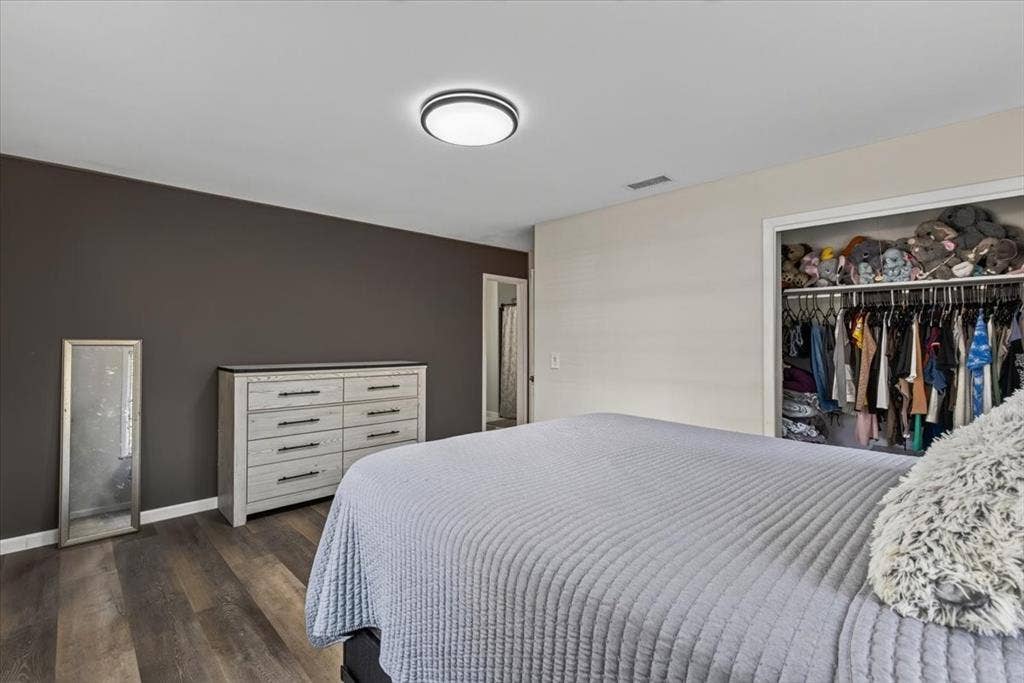 925 Maryland Drive, Athens, TX 75751 Bedroom featuring rich wood-finish flooring, a contemporary flush-mount ceiling light, and a built-in closet with hanging rods and shelf storage