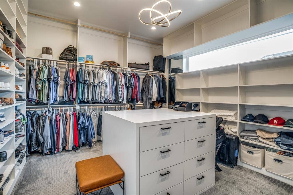 3766 Manana Drive, Dallas, TX 75220 Spacious closet featuring a window providing natural light along with recessed lighting and a modern designer chandelier so you will never make the mistake of putting on 2 different colored shoes. There is ample space for hanging clothes, shoes, bags and luggage and an island with extra drawer space.