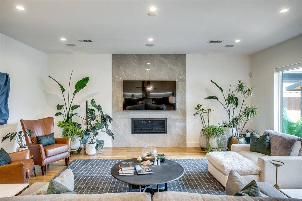 3766 Manana Drive, Dallas, TX 75220 Living room featuring surround sound, wood finished floors, and a premium floor to ceiling ELEGANZA tiled auto ignite fireplace. surround sound and recessed lighting can be controlled by the smart panel.