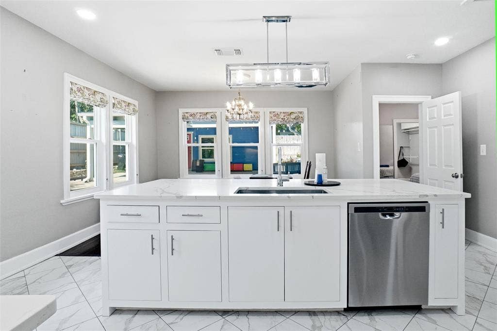2306 Western Avenue, Fort Worth, TX 76107 Central kitchen island featuring a white countertop, undermount sink, and stainless steel dishwasher