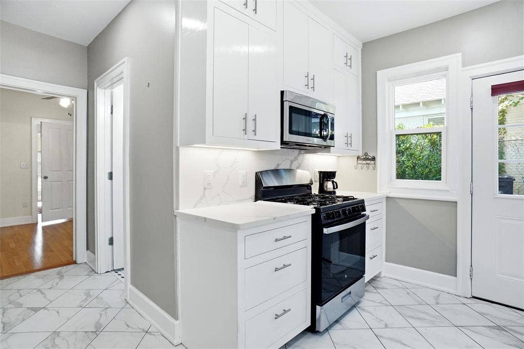 2306 Western Avenue, Fort Worth, TX 76107 Kitchen featuring bright white cabinetry, stainless steel microwave, gas range, marble-patterned countertops, and tile flooring