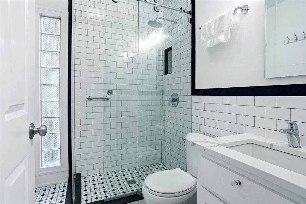 2306 Western Avenue, Fort Worth, TX 76107 Bathroom featuring white subway tile, a glass-enclosed shower, black and white mosaic floor tile, a white vanity with a rectangular sink, and a glass block window