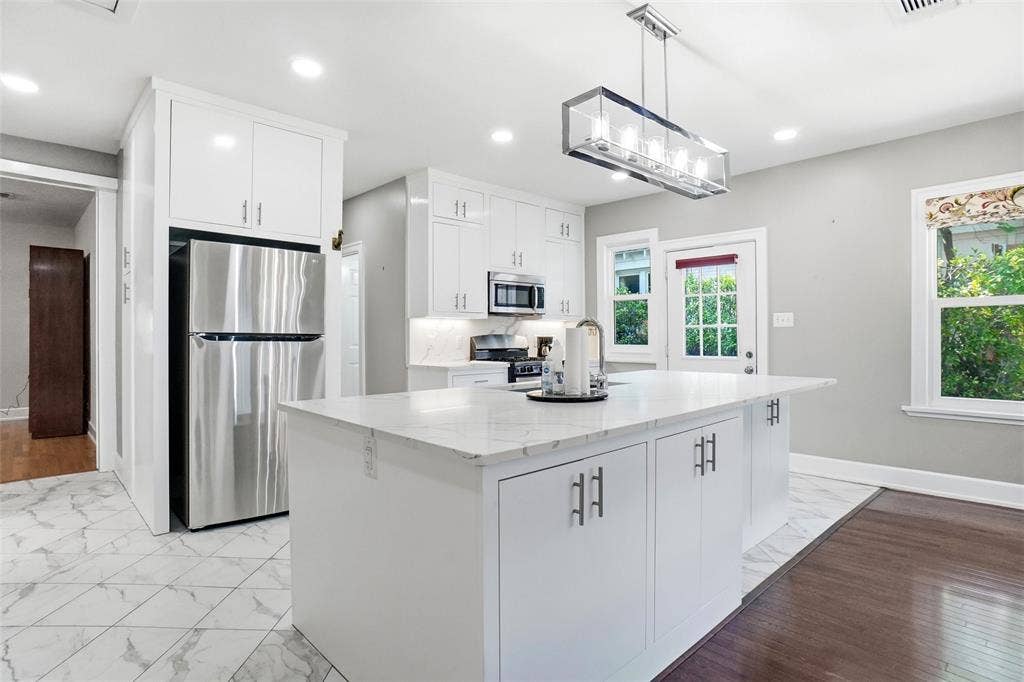 2306 Western Avenue, Fort Worth, TX 76107 Modern kitchen featuring white cabinetry, a large center island with a quartz-finish countertop, stainless steel appliances, and a contemporary linear chandelier