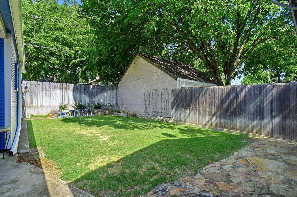 2306 Western Avenue, Fort Worth, TX 76107 Private backyard space featuring a manicured lawn, flagstone patio, and mature perimeter trees