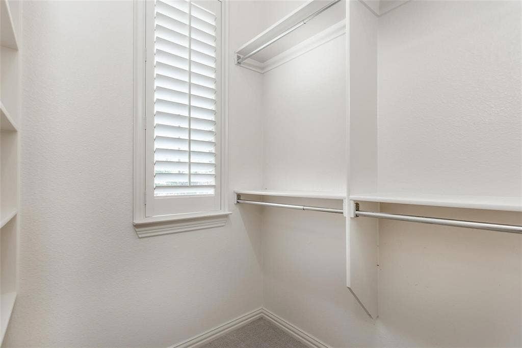921 Pine Burst Drive, Allen, TX 75013 Built-in closet system featuring multiple shelves and hanging rods, a window with plantation shutters, and light-colored carpeting