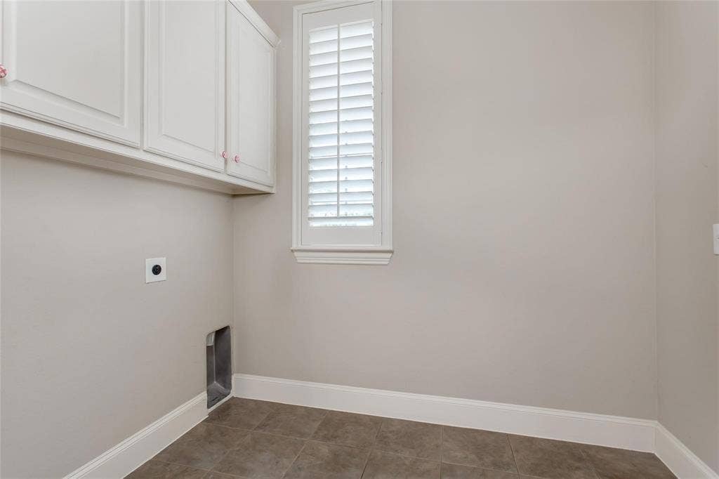 921 Pine Burst Drive, Allen, TX 75013 Utility area featuring white upper cabinetry, tiled flooring, a window with white louvered shutters, and light neutral wall tones